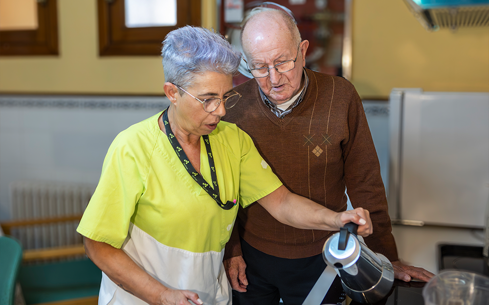 Una trabajadora de Zaintzen sirviendo un café a un residente